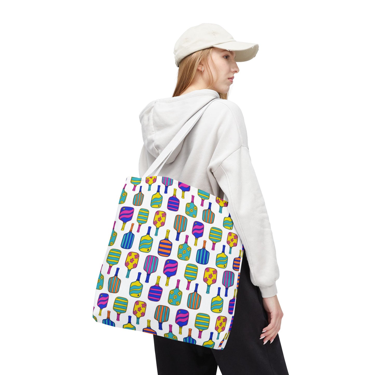 woman holding white tote bag with colorful pattern full of the best pickleball paddles