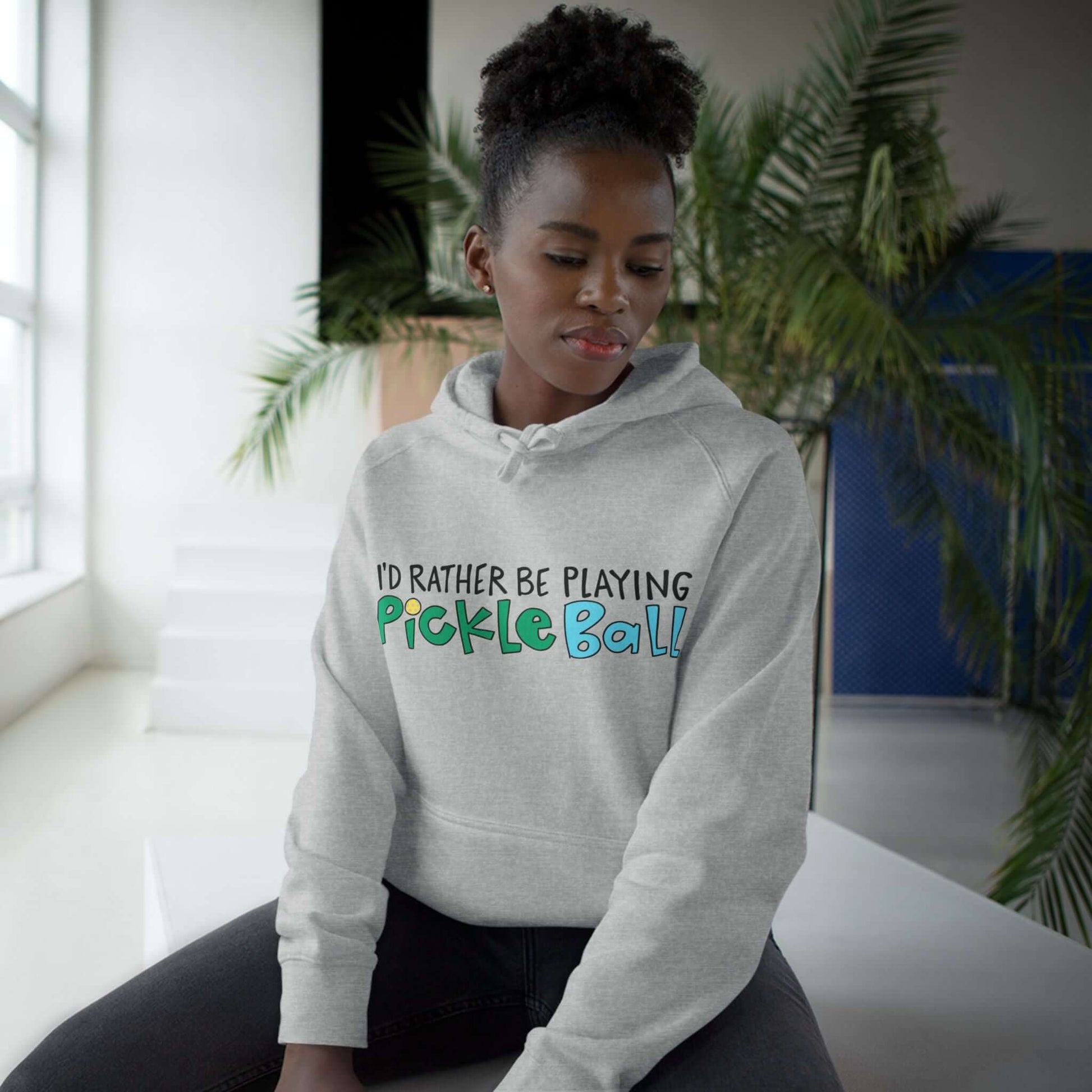 Woman in Darker Gray hoodie with 'I'd Rather Be Playing Pickleball' on front in colorful handlettering