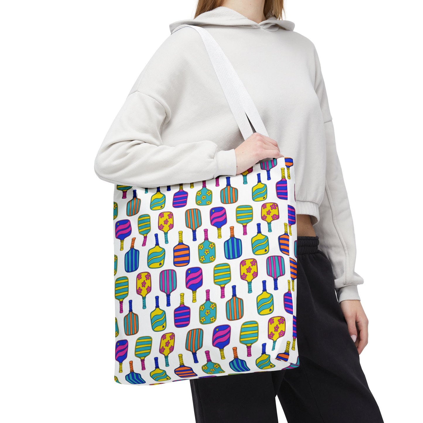 woman holding white tote bag with colorful pattern full of the best pickleball paddles