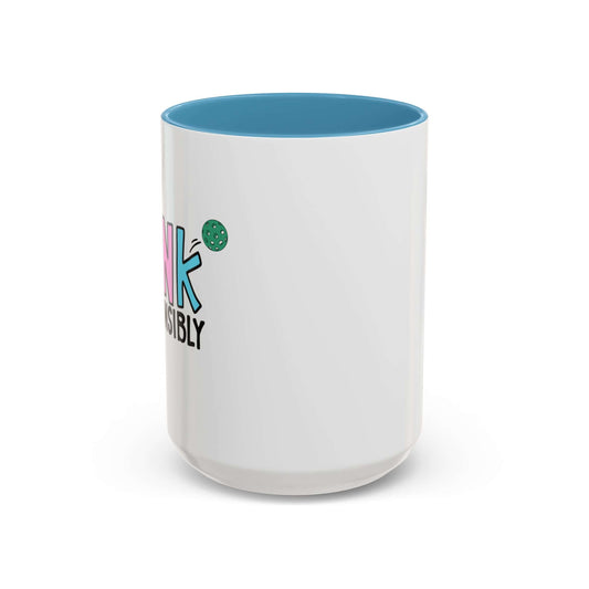 white coffee mug with light blue handle and blue inside of mug. Colorful handlettering says 'Dink Responsibly' with a pickleball flying on top of it